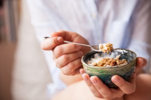 person scooping spoonful of nuts and yogurt