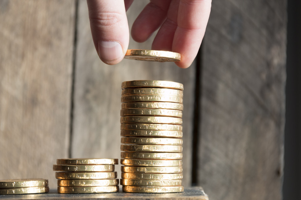 Hand put coin to money, financial growth concept with stacks of golden coins