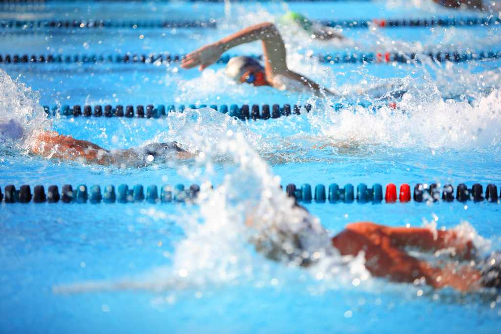 Three swimmers competing with each other in a freestyle race.