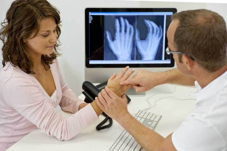 Doctor and patient looking at x-ray and hand in doctor's office