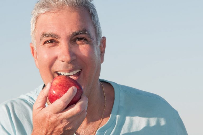 elderly man eating an apple