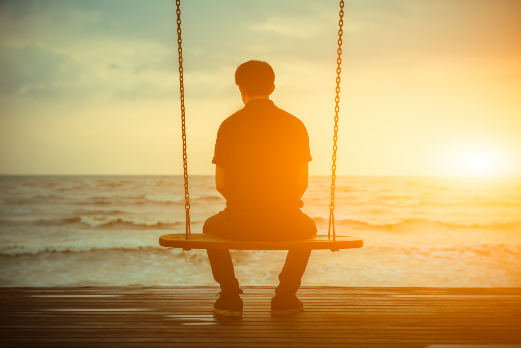 alone man sitting on a swing