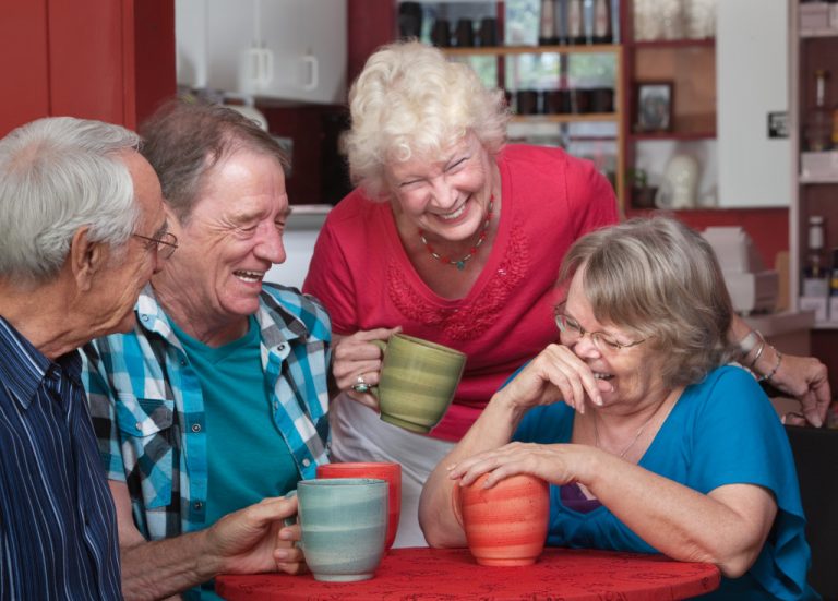 Group of seniors laughing while having coffee at the table