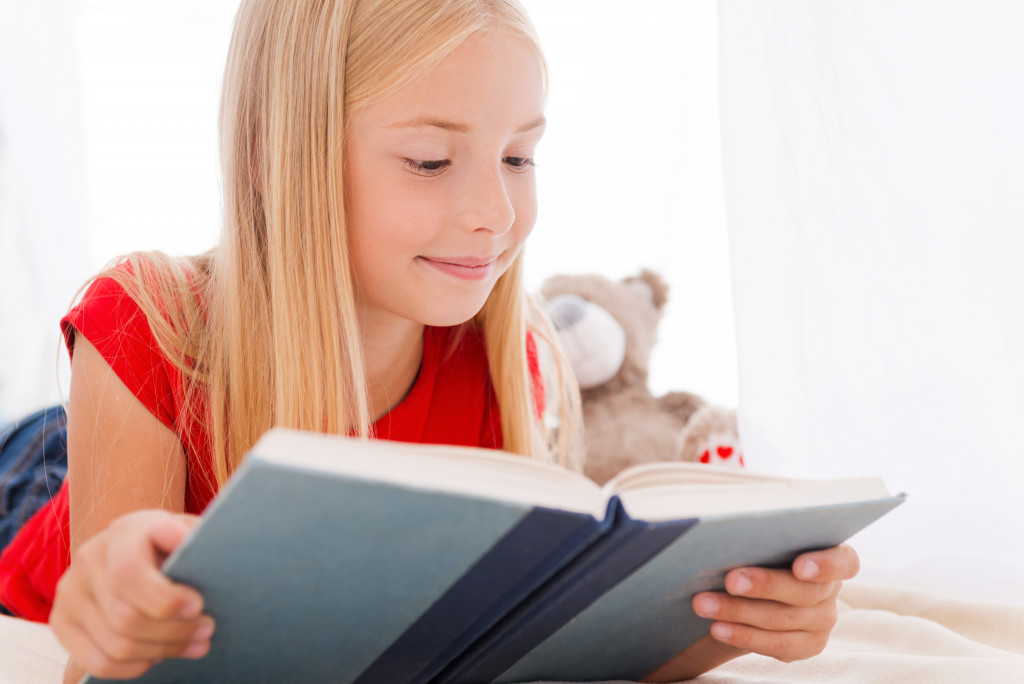 young girl in her bed reading a book