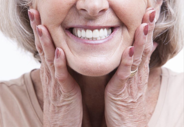 an elderly woman is smiling and showing her white teeth