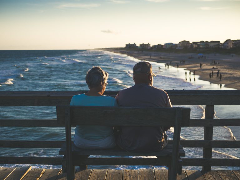 two elderly people sitting by the sea