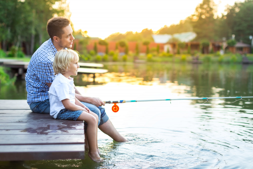 Father and son fishing on a lake by the dock