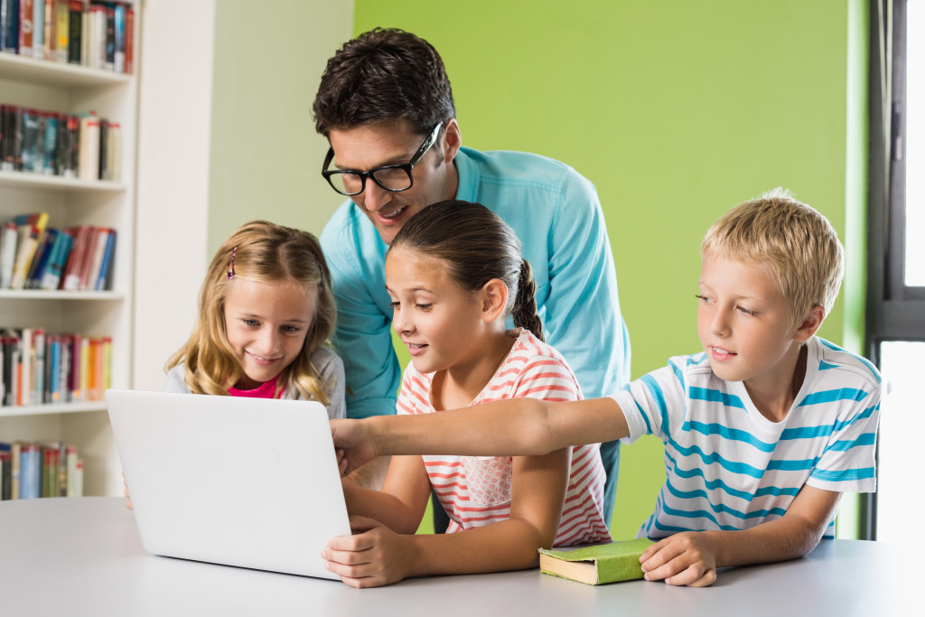 Three kids and father helping them learn