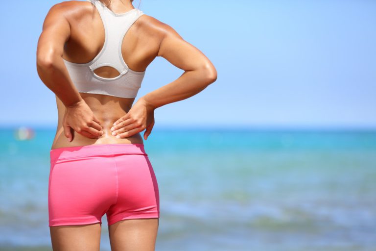 a woman in the beach with back pain