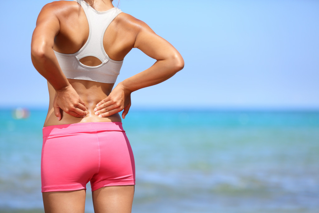 a woman in the beach with back pain