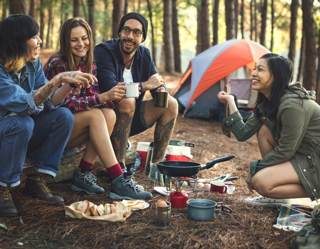 Group of friends eating while camping at a park.