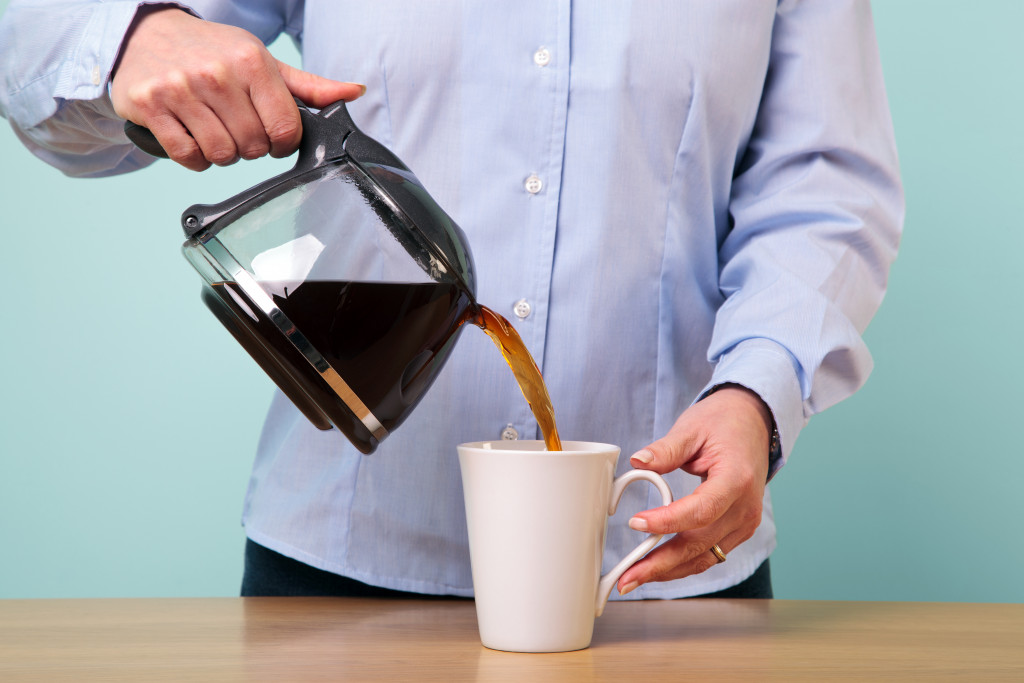 Someone pouring coffee from a pot to a mug