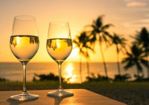 Two wine glasses with a beach sunset background
