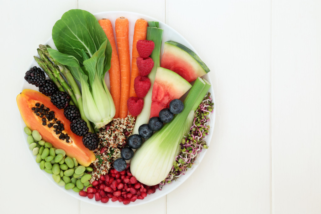 A bowl of fruits and vegetables on a white table.