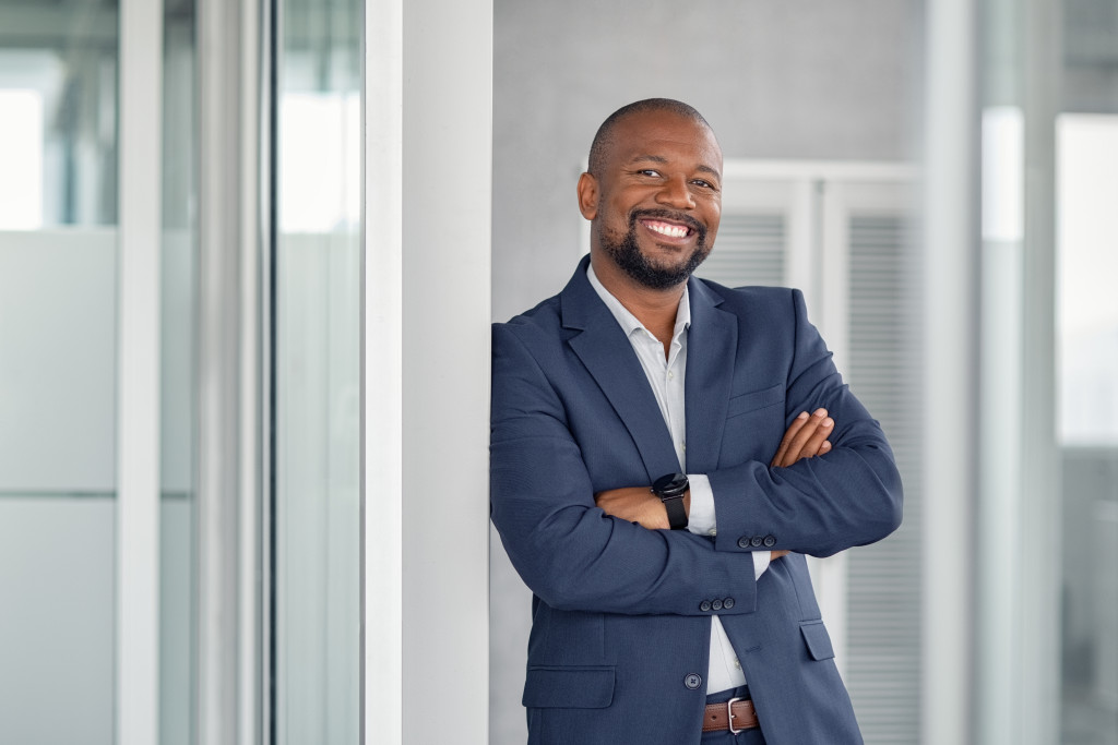 a man leaning on a wall dressed in business suit and smiling confidently