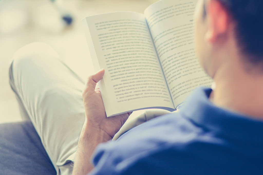 A man reading a book on the couch